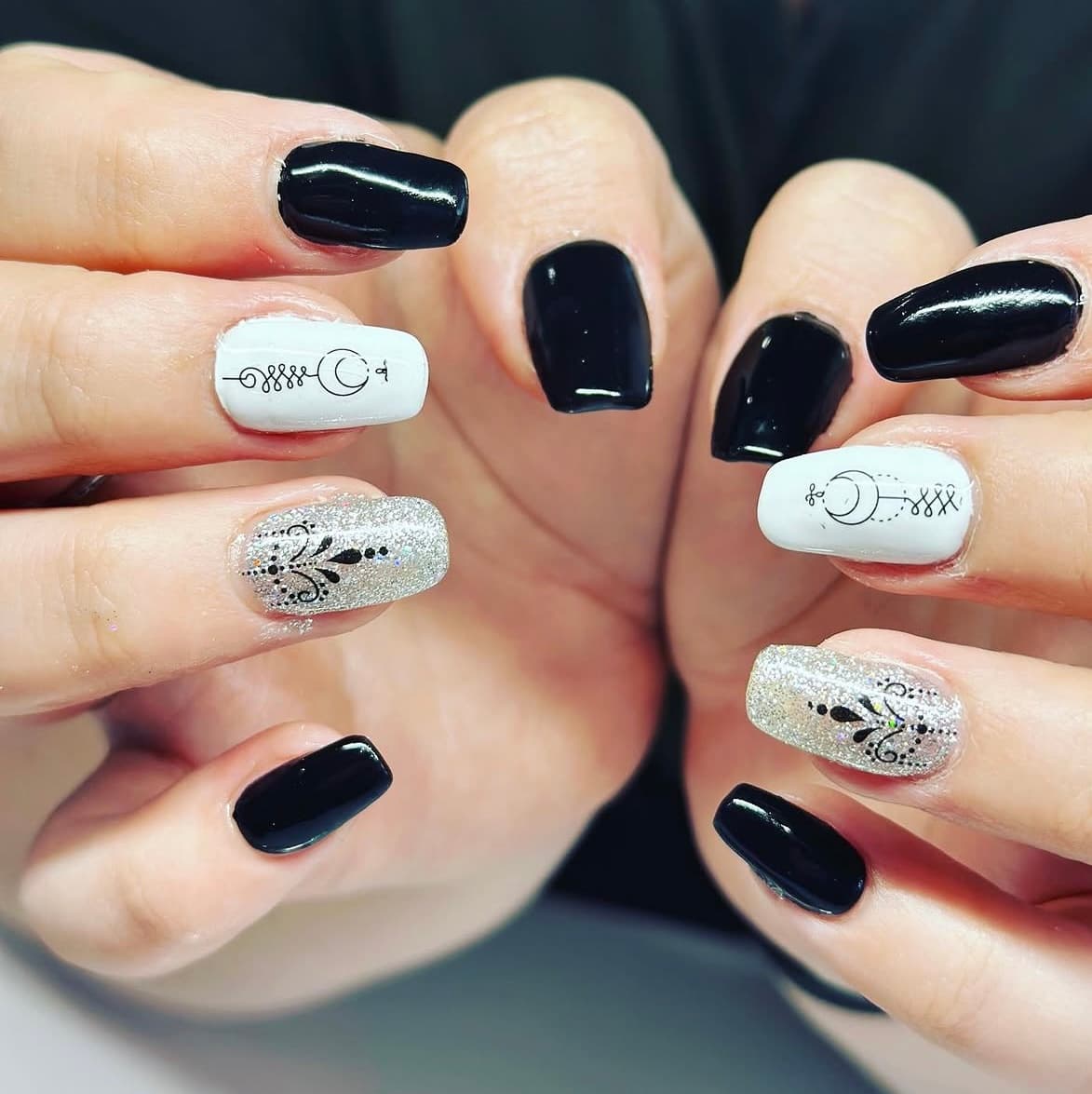 Glossy black, white and silver glitter nails with delicate black nail art