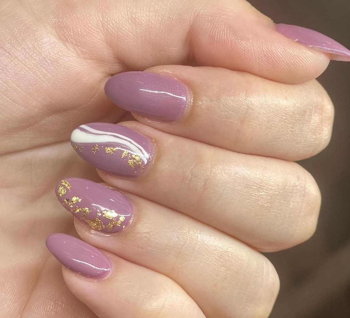 Mauve almond nails with gold foil and white wave accents