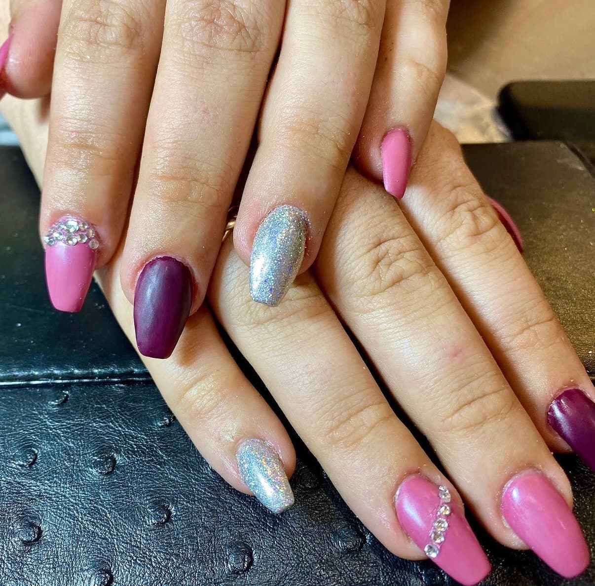 Pink and plum nails with silver glitter and rhinestone accents