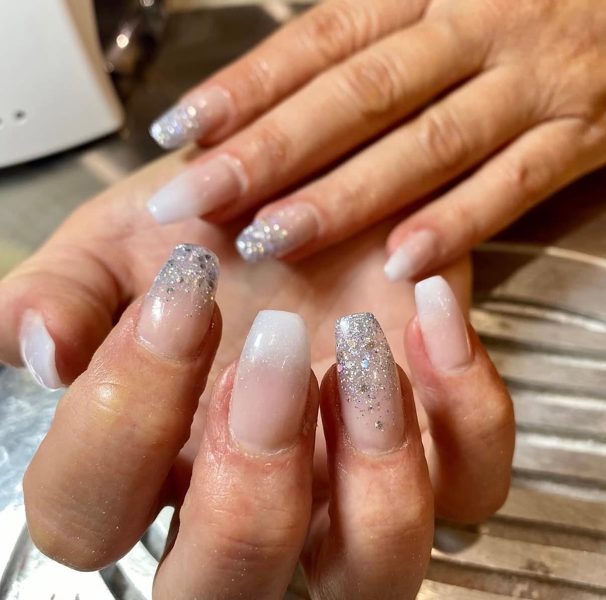 Soft pink and white ombre nails with silver glitter accents